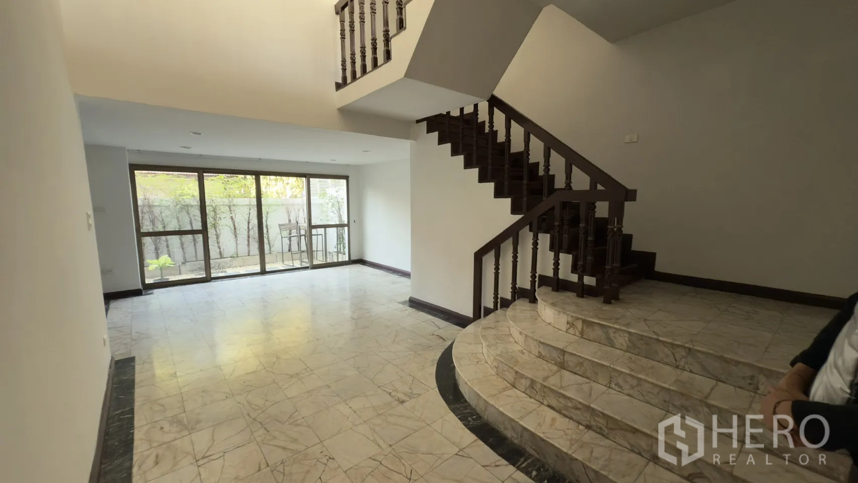 Townhouse for rent in Watthana, Bangkok - Open-plan lounge showing curved marble steps leading to the staircase and patio doors.
