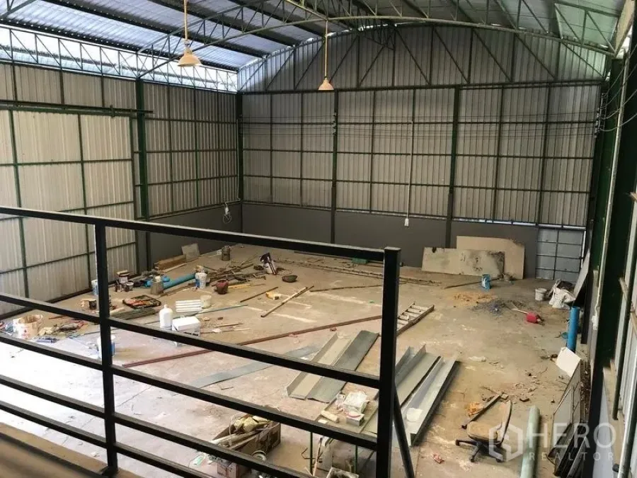 Warehouse for rent in Lam Luk Ka, Pathum Thani - High-ceiling steel-frame warehouse with skylights and mezzanine view over a large open work floor.
