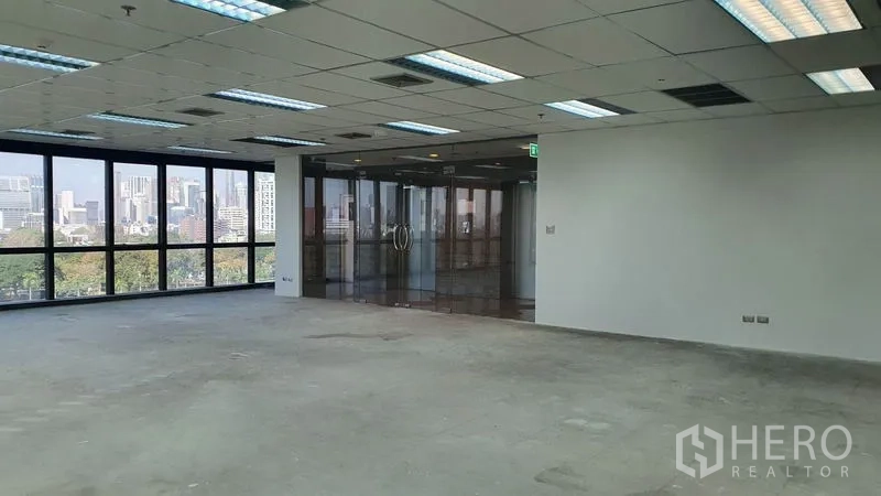 Office Space for rent in Watthana, Bangkok - Spacious office interior with city-view windows and a full glass entry wall.