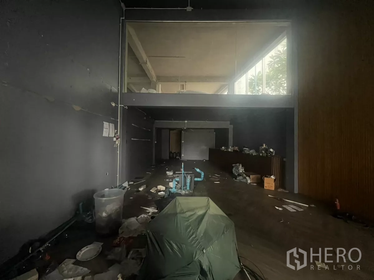 Shophouse for rent in Khlong Toei, Bangkok - Deep shophouse floor with high ceiling, mezzanine room and long counter along dark walls, vacant and refurb-ready.
