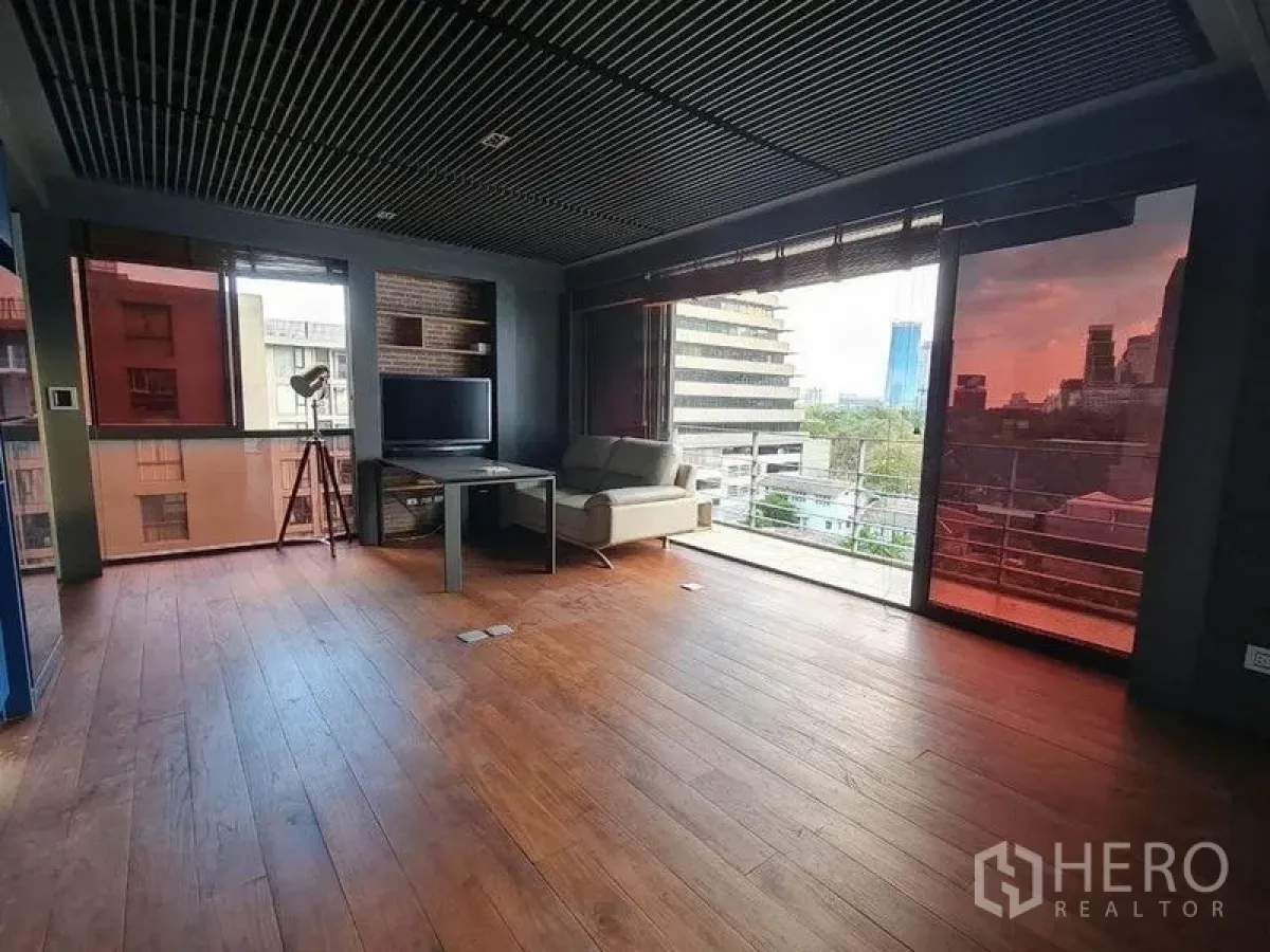 Condominium for sale in Pathum Wan, Bangkok - Bright living room with sofa and panoramic windows facing the city.