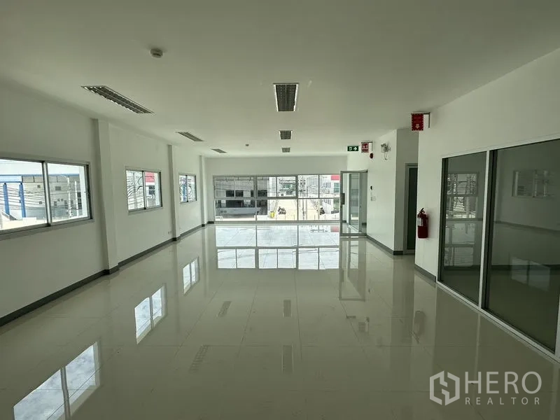 Factory for rent in Mueang Samut Prakan, Samut Prakan - Second-floor office space with glass partitions and wide windows overlooking the yard.
