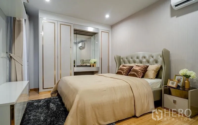 Detached House for sale in Lam Luk Ka, Pathum Thani - Second bedroom with upholstered bed, wardrobe and wood flooring.