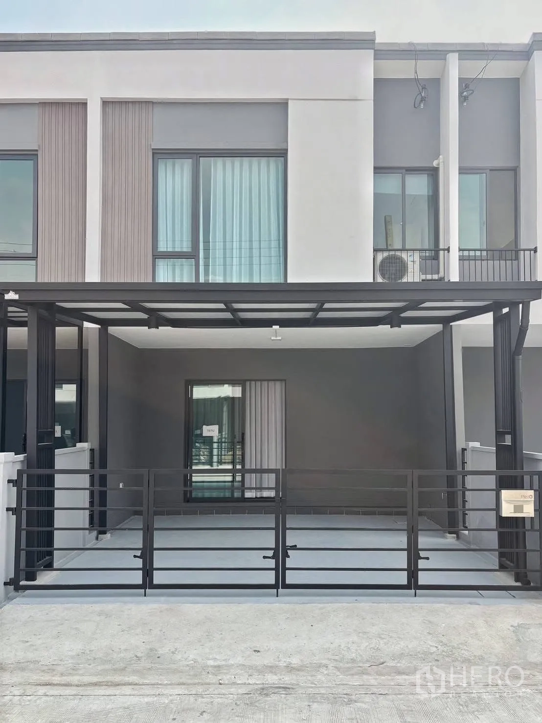 Townhouse for rent in Bang Phli, Samut Prakan - Contemporary two-story townhouse facade with covered carport, sliding door and balcony.