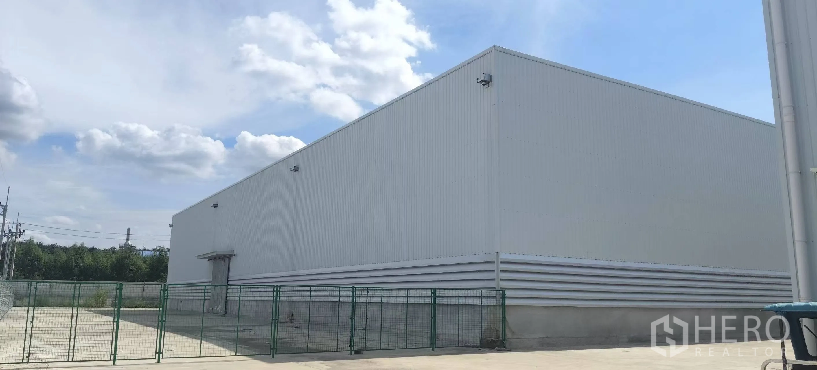 Factory for rent in Plaeng Yao, Chachoengsao - Modern white factory exterior with corrugated panels, security cameras, and a fenced yard.