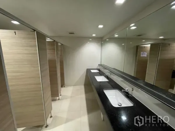 Office Space for rent in Ratchathewi, Bangkok - Shared washrooms with long black countertop, mirrors and wood-style stalls in Bangkok office building.