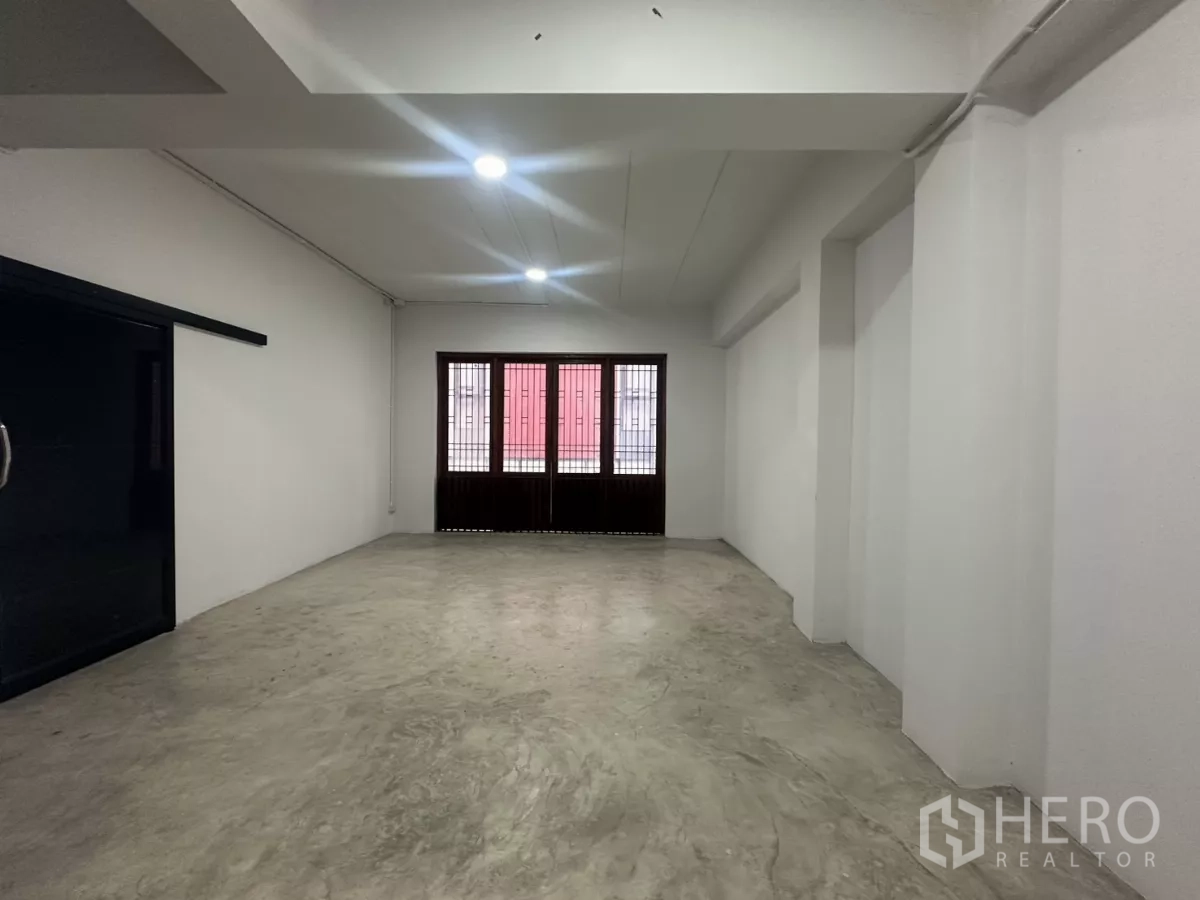 Home Office for rent in Pathum Wan, Bangkok - Large open room with concrete floor and a window with wooden shutters.