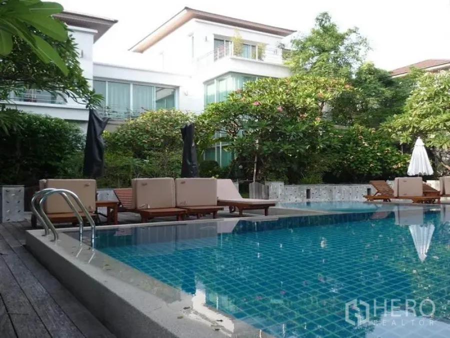 Detached House for rent in Khan Na Yao, Bangkok - Lush garden pool with sun loungers beside modern detached houses in Khan Na Yao