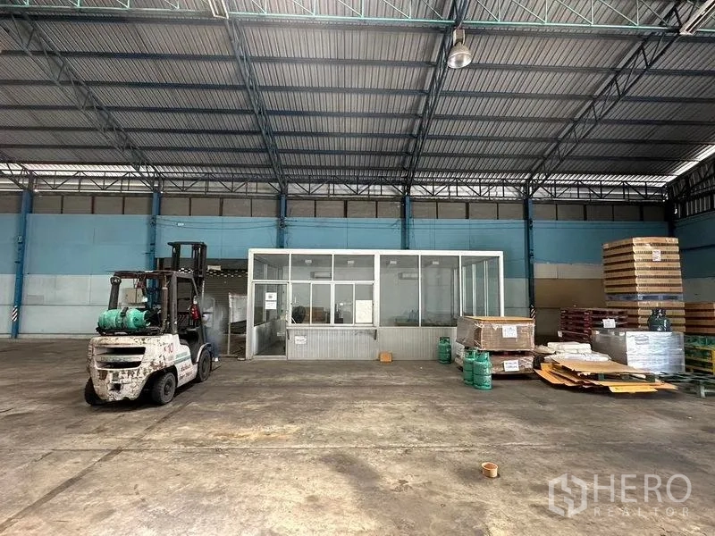 Warehouse for rent in Bang Pa-in, Phra Nakhon Si Ayutthaya - Glass-partitioned office inside the warehouse with pallets and materials nearby.