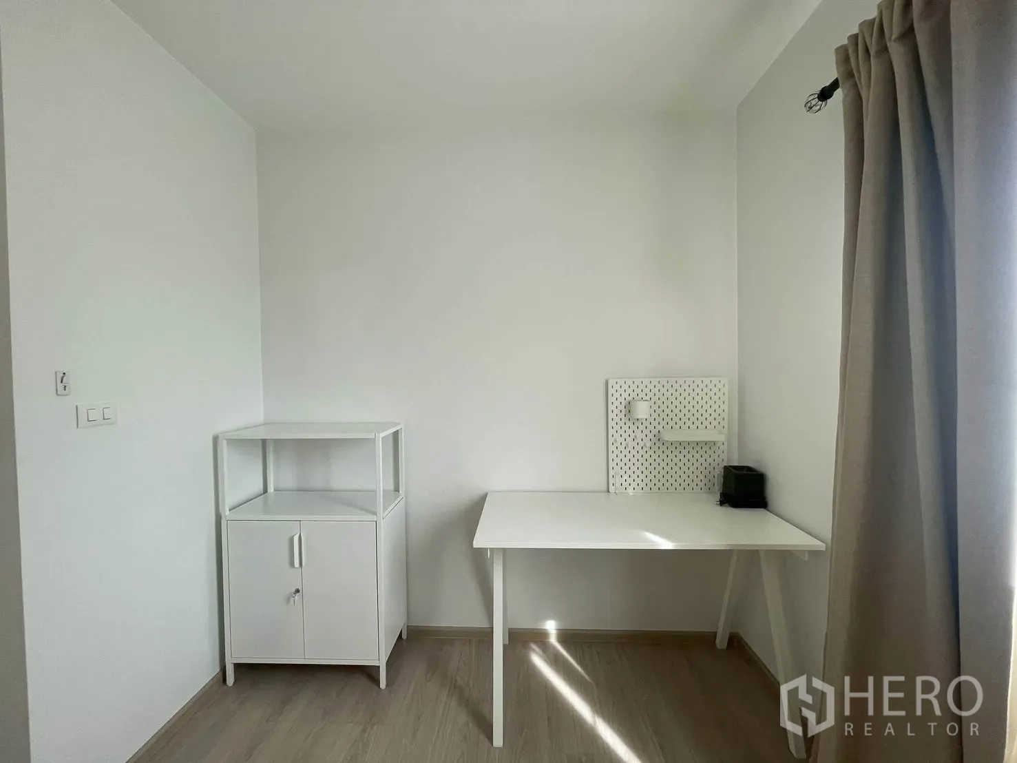 Townhouse for rent in Bang Phli, Samut Prakan - Bright small room with desk, cabinet and curtained window.