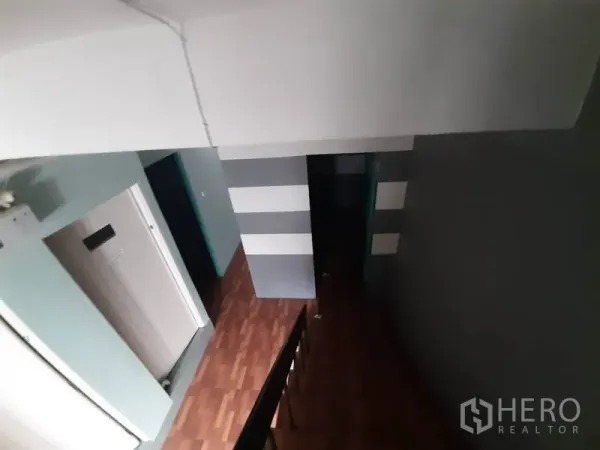 Shophouse for rent in Watthana, Bangkok - Upper-floor corridor and staircase with gray striped walls and wood-style floors.