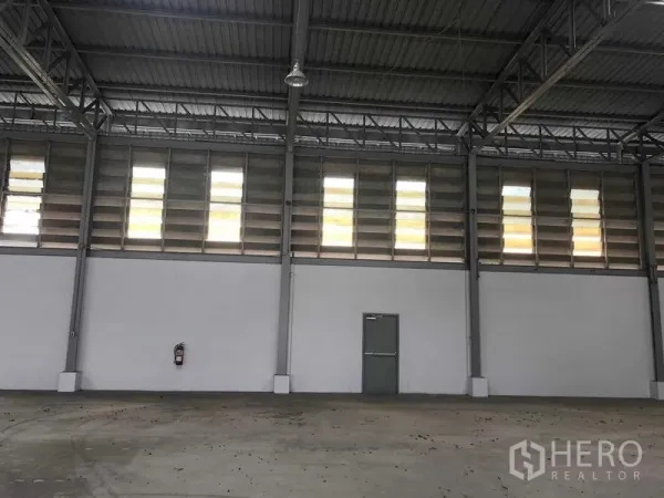 Warehouse for rent in Prawet, Bangkok - High-ceiling warehouse interior with steel trusses, clerestory louver windows and concrete floor.