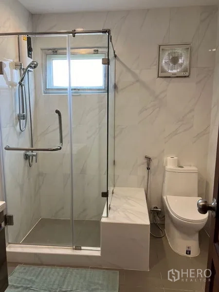 Detached House for sale in Mueang Pathum Thani, Pathum Thani - Second bathroom with glass shower, built-in bench and ventilation window.