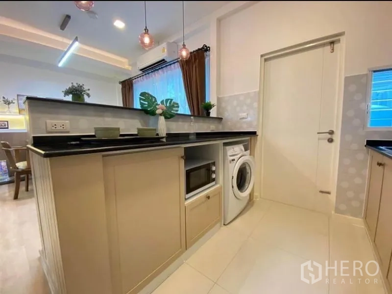 ทาวน์เฮาส์ ให้เช่าในPrawet, Bangkok - เคาน์เตอร์ครัวแบบเพนนินซูลา ท็อปหินสีดำ มีไมโครเวฟและเครื่องซักผ้าบิวท์อิน ใต้โคมแขวน