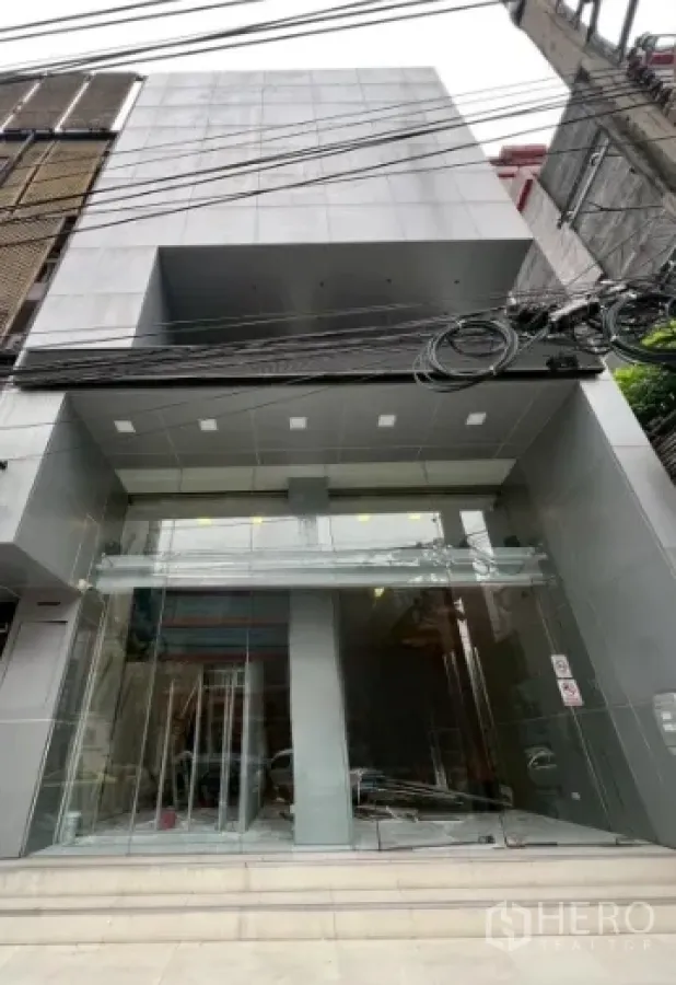 พื้นที่ขายปลีก ให้เช่าในWatthana, Bangkok - อาคารค้าปลีกสไตล์โมเดิร์น ด้านหน้าเป็นกระจกสูงเต็มบานและผนังสีเทาเรียบ