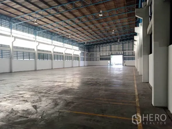 Factory for rent in Samut Prakan - Spacious factory interior in Phra Pradaeng with high steel truss roof, polished concrete floor and long clerestory windows.