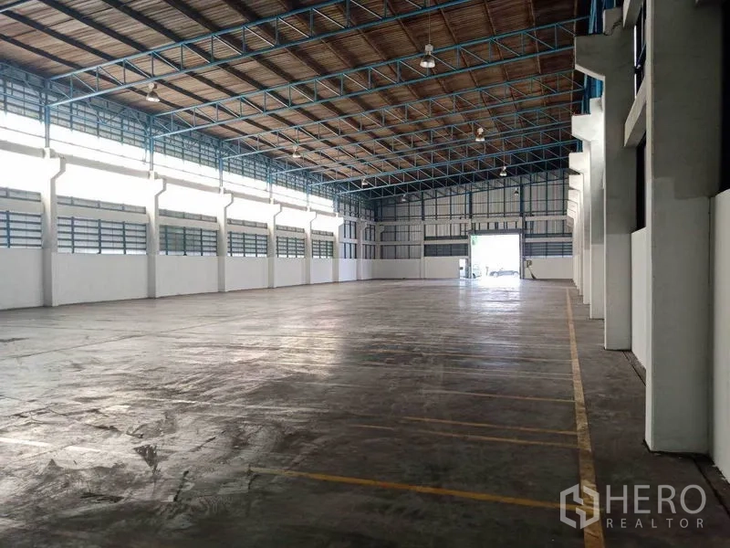 Factory for rent in Samut Prakan - Spacious factory interior in Phra Pradaeng with high steel truss roof, polished concrete floor and long clerestory windows.