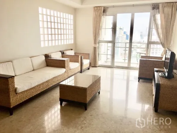 Condominium for rent in Khlong Toei, Bangkok - Sunlit lounge with woven sofas and balcony doors opening to city views.