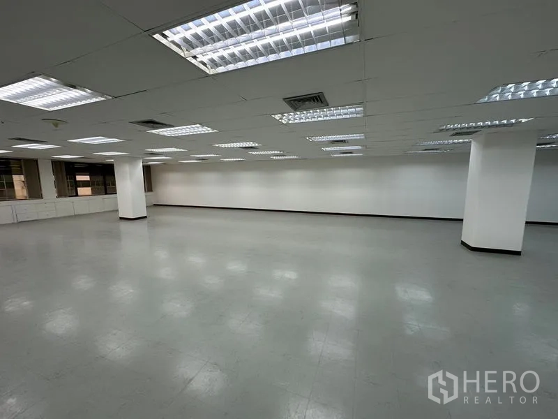 Office Space for rent in Watthana, Bangkok - Large empty office floor with grid ceiling lights, white walls, grey vinyl flooring and structural columns.