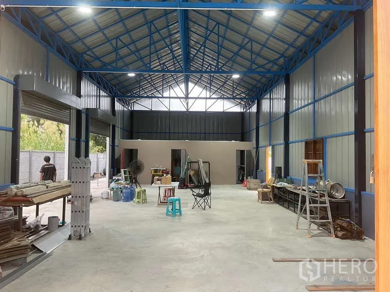 Warehouse for rent or sale in Nong Chok, Bangkok - High‑bay warehouse interior showing blue steel trusses, skylights and an open 150 sq m floor.