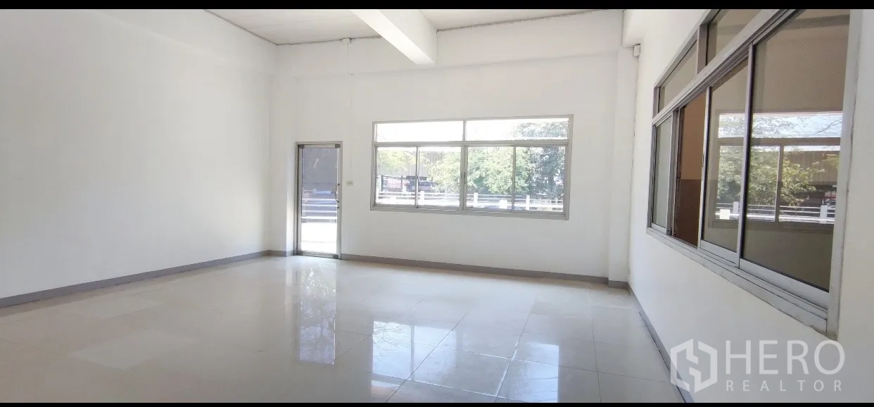 Factory for rent in Mueang Samut Prakan, Samut Prakan - Ground-floor office room with tiled floor and large windows overlooking the yard.
