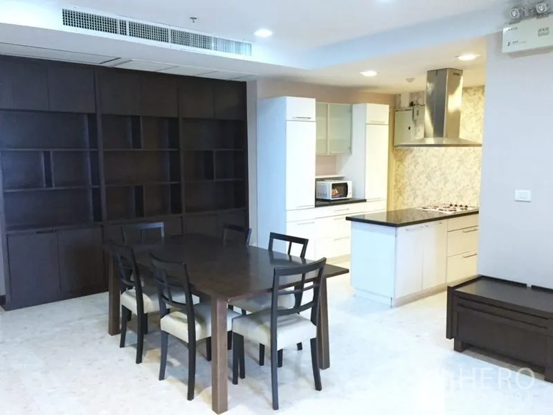 Condominium for rent in Khlong Toei, Bangkok - Open kitchen with island, range hood, and a six-seat dining table.