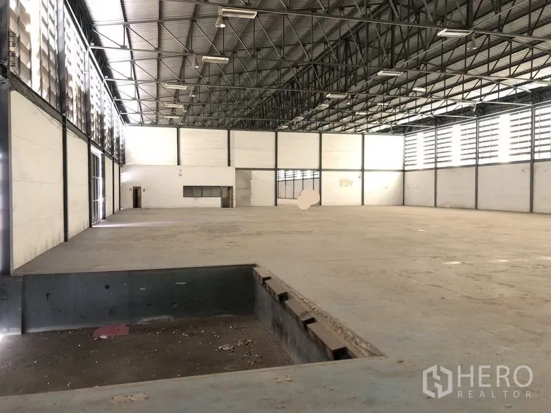 Warehouse for rent in Khlong Luang, Pathum Thani - Expansive warehouse floor with dock-level pit, skylight-lit aisle and ventilation louvers along the wall.