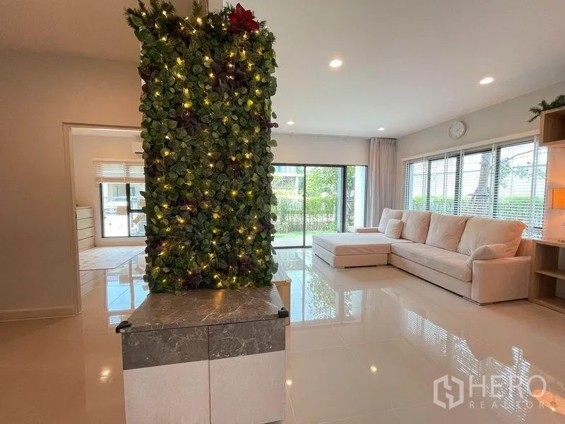 Detached House for sale in Pak Kret, Nonthaburi - L-shaped sofa in a light-filled living room with sliding doors to the garden.