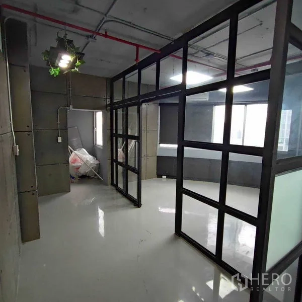 Office Space for rent in Watthana, Bangkok - Corridor beside a glass meeting room leading to a storage area with an industrial finish.