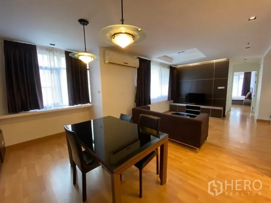 Condominium for rent in Khlong Toei, Bangkok - Open-plan living space leading to the bedroom, with dining table and sofa.