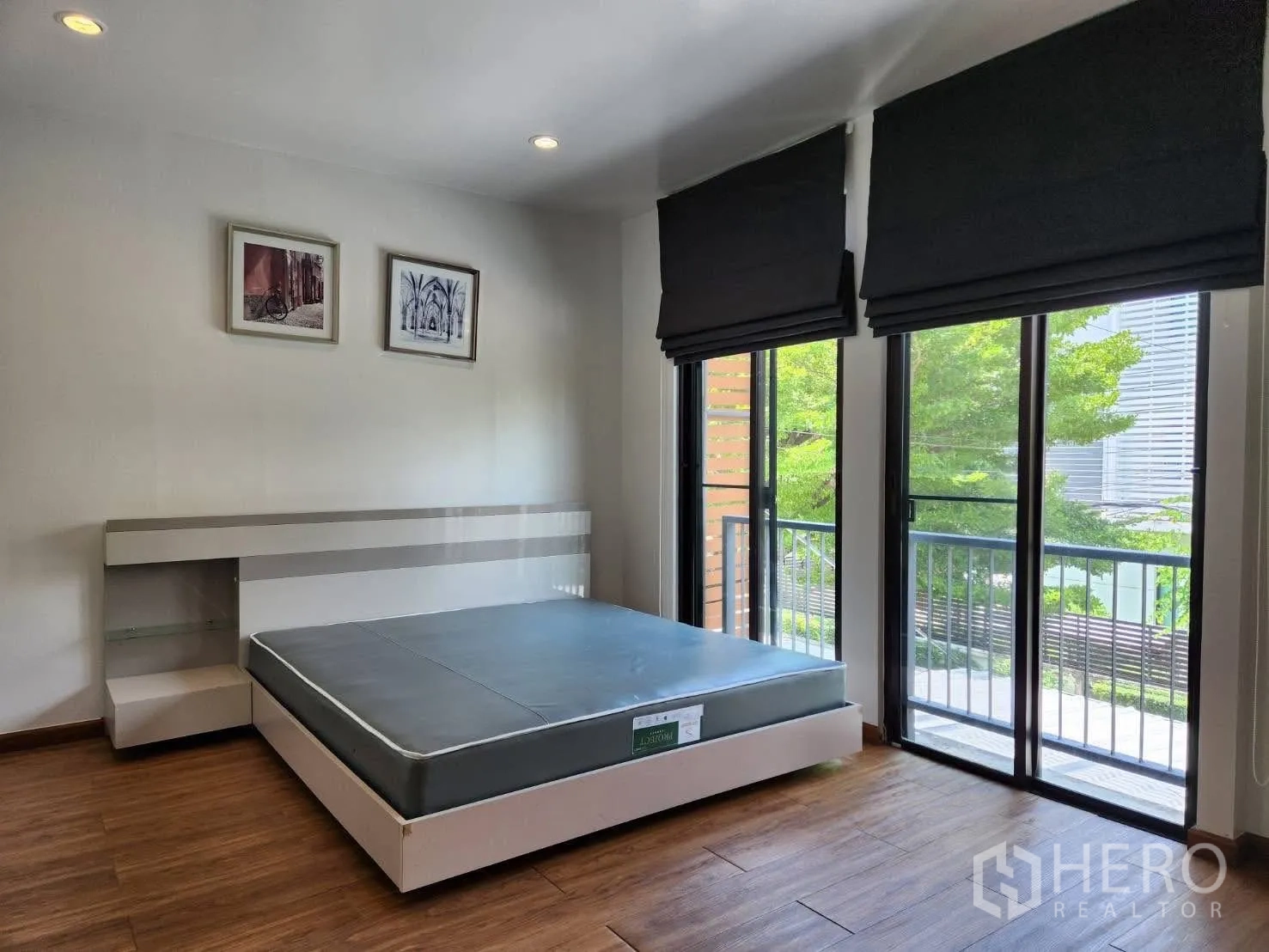 Townhouse for rent in Suan Luang, Bangkok - Bedroom with sliding doors opening to a balcony and tree views.