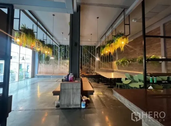 Retail Space for rent - Open-plan restaurant interior with pendant lights, greenery chandeliers and long banquette seating.