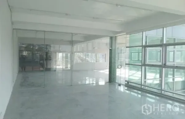 Warehouse for rent or sale in Prawet, Bangkok - Bright office or showroom space with large windows and full-height glass partitions.