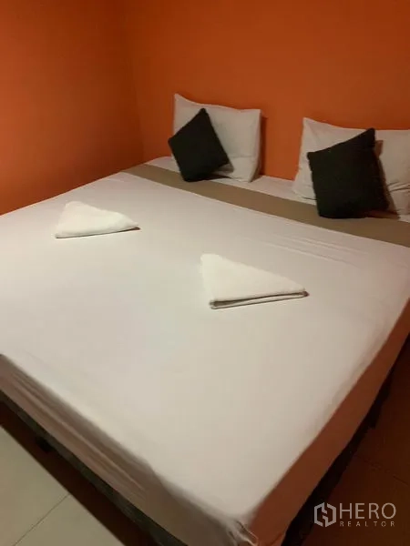 Retail Space for rent in Khlong Toei, Bangkok - King-size bed in an orange-themed room with folded towels on top.