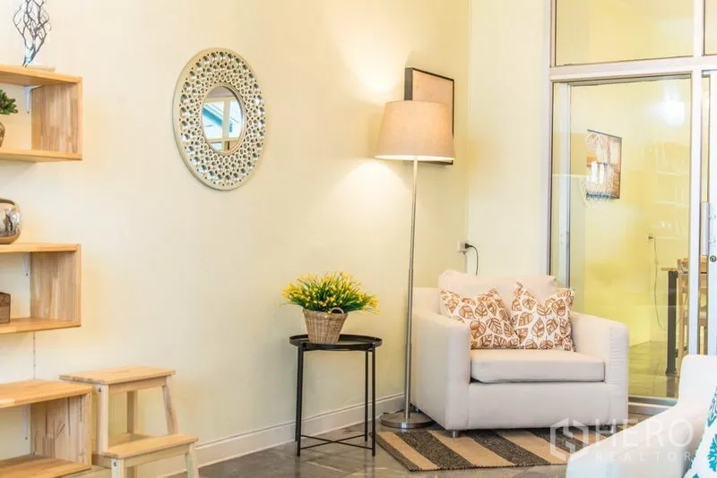 Home Office for rent in Suan Luang, Bangkok - Cozy corner with armchair, floor lamp and round mirror by glass doors.