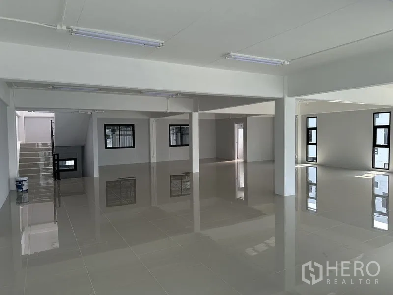 Warehouse for rent in Bang Phli, Samut Prakan - Open-plan office floor with windows, staircase access, and shiny tile surfaces.