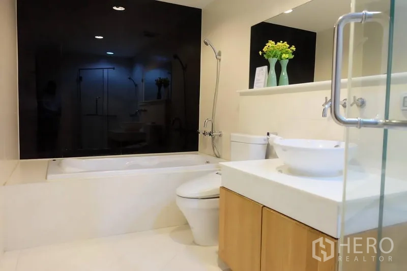 Condominium for rent in Khlong Toei, Bangkok - Modern condo bathroom with bathtub, vessel sink, glass shower and black accent wall in Khlong Toei