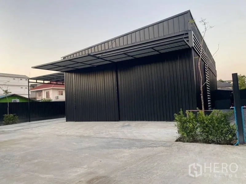 Warehouse for rent in Wang Thonglang, Bangkok - Front facade of the warehouse with sliding metal doors, secure fence and generous parking apron.