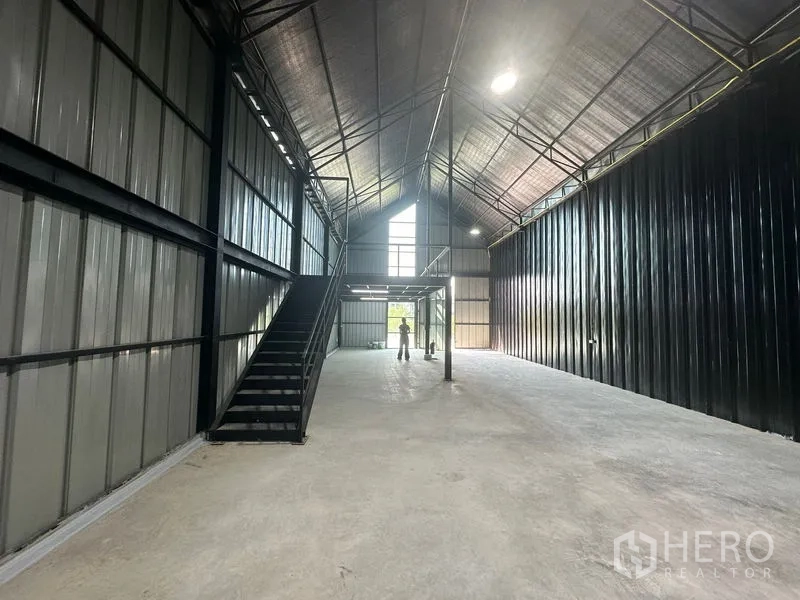 Warehouse for rent in Bueng Kum, Bangkok - Long aisle view of the warehouse showing stairs to a mezzanine and clerestory windows.