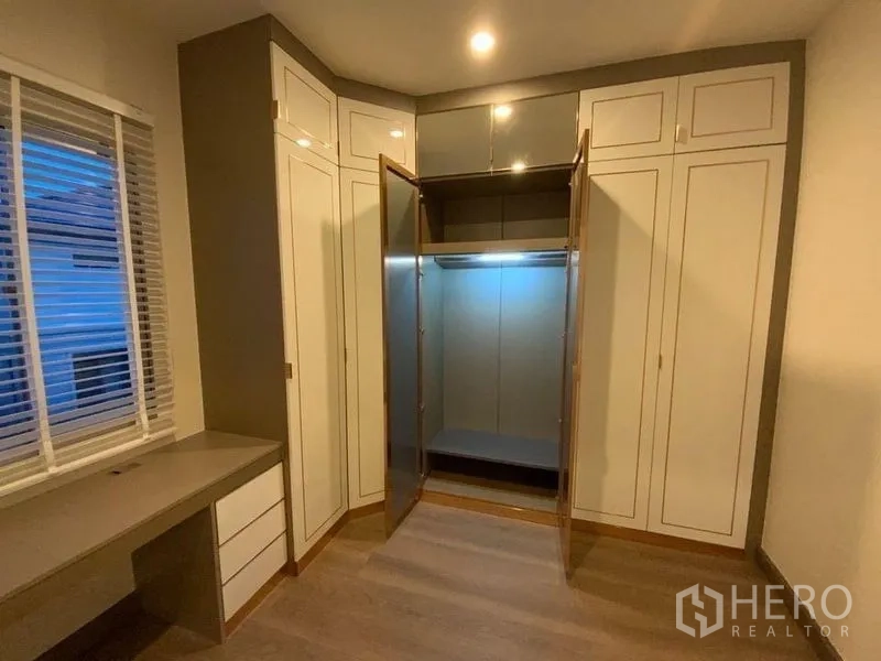 Townhouse for rent in Prawet, Bangkok - Built-in corner wardrobe with glass doors and a study desk.