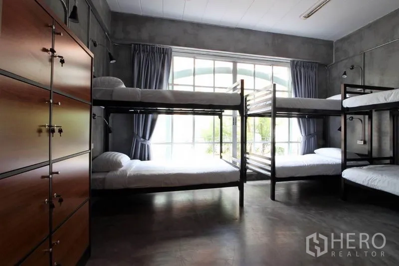 Office Space for rent or sale in Bang Rak, Bangkok - Large dorm room with four bunk beds, lockers, and full-height windows.