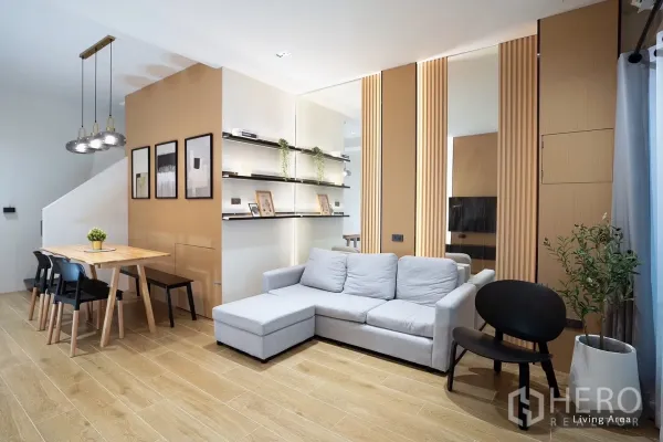 联排别墅 出租在Huai Khwang, Bangkok - 开放式客餐厅，L型沙发、壁龛层板与木质装饰。