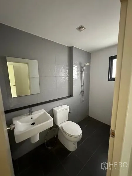独立式住宅 出售在Bang Khen, Bangkok - 灰白色调浴室，带手持花洒和通风窗。
