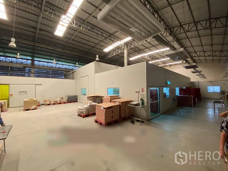 Warehouse for rent in Bueng Kum, Bangkok - Open production area with insulated partition rooms, windows, pallets, and overhead industrial lighting.