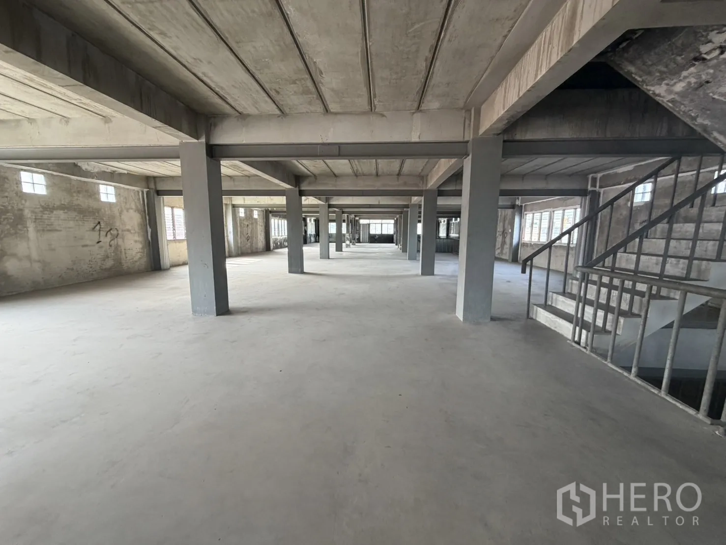 Factory for rent or sale in Bang Bon, Bangkok - Open-plan factory floor with concrete columns and an internal staircase.