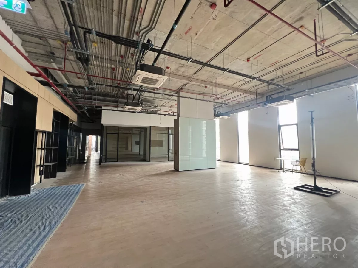 Retail Space for rent - Expansive retail area with a central glass feature, floor-to-ceiling windows and exposed services ceiling.