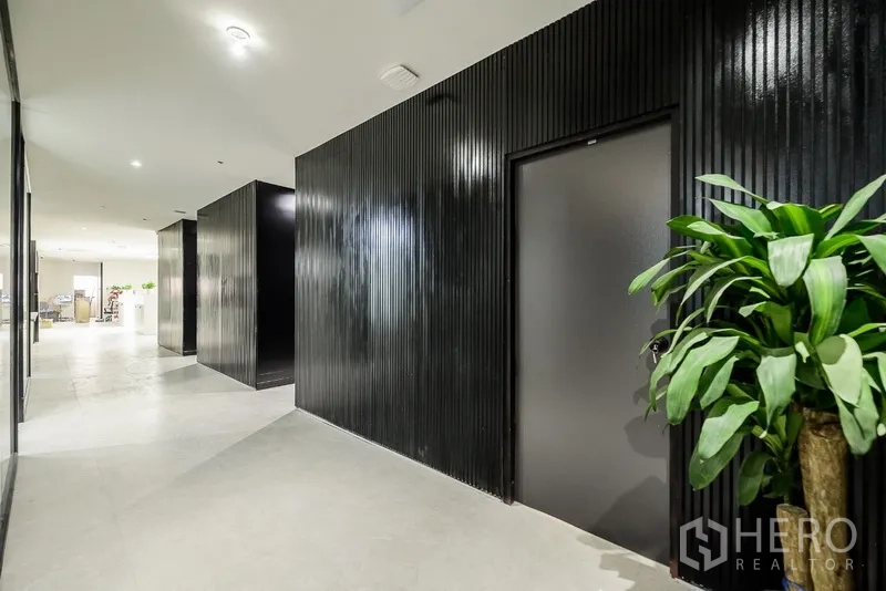Office Space for rent or sale in Huai Khwang, Bangkok - Sleek corridor with glossy black feature walls and a decorative potted plant.