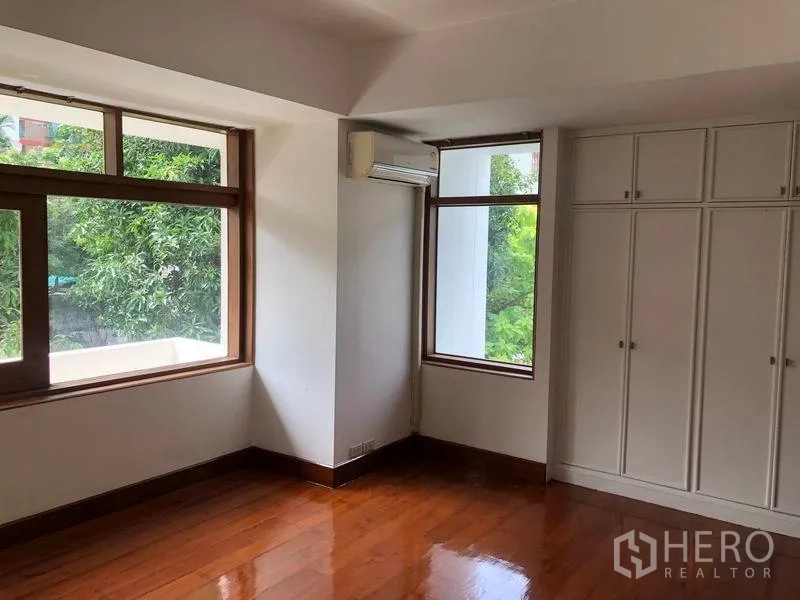 Detached House for rent in Watthana, Bangkok - Corner bedroom with built-in wardrobes, wood floors and large windows.