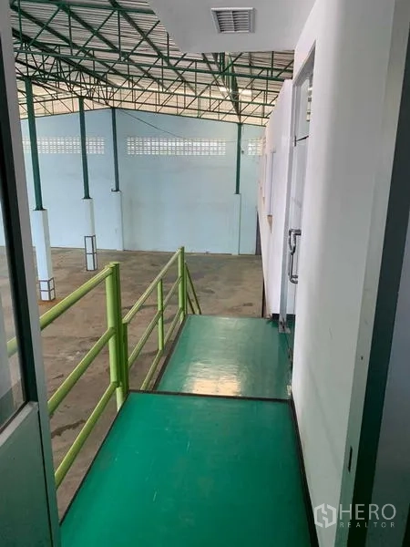 Warehouse for rent in Bang Phli, Samut Prakan - Mezzanine walkway with green handrails overlooking the high-clearance warehouse below.