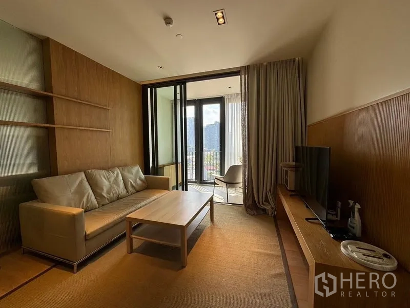 Condominium for rent - Warm-toned living room with sofa, coffee table, TV console and sliding doors to a balcony with city skyline view.